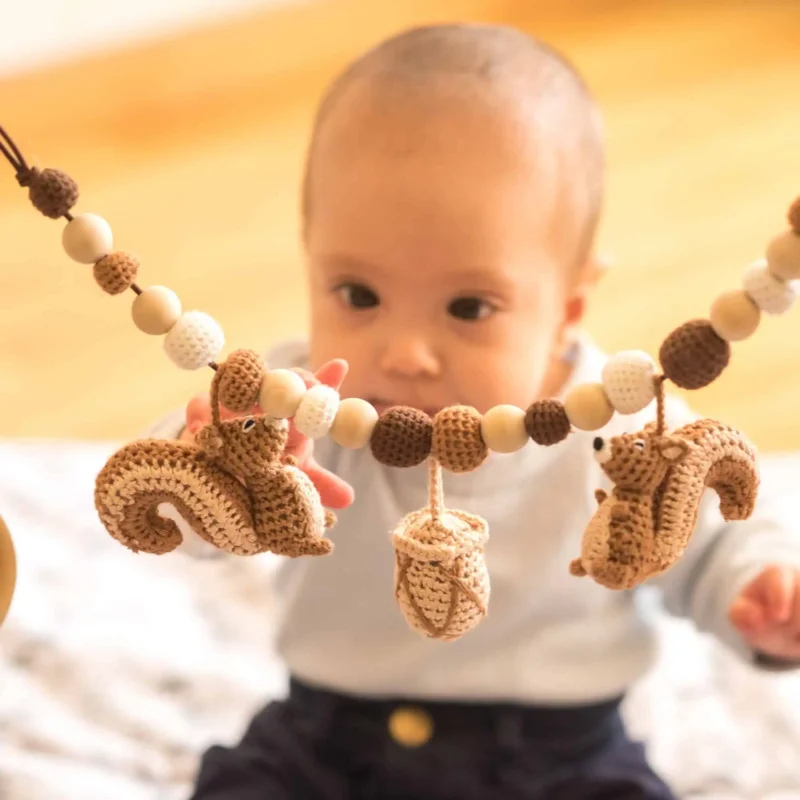 Lifestyle – Baby betrachtet die Kette Baby betrachtet die gehäkelte Kinderwagenkette mit neugierigem Blick.