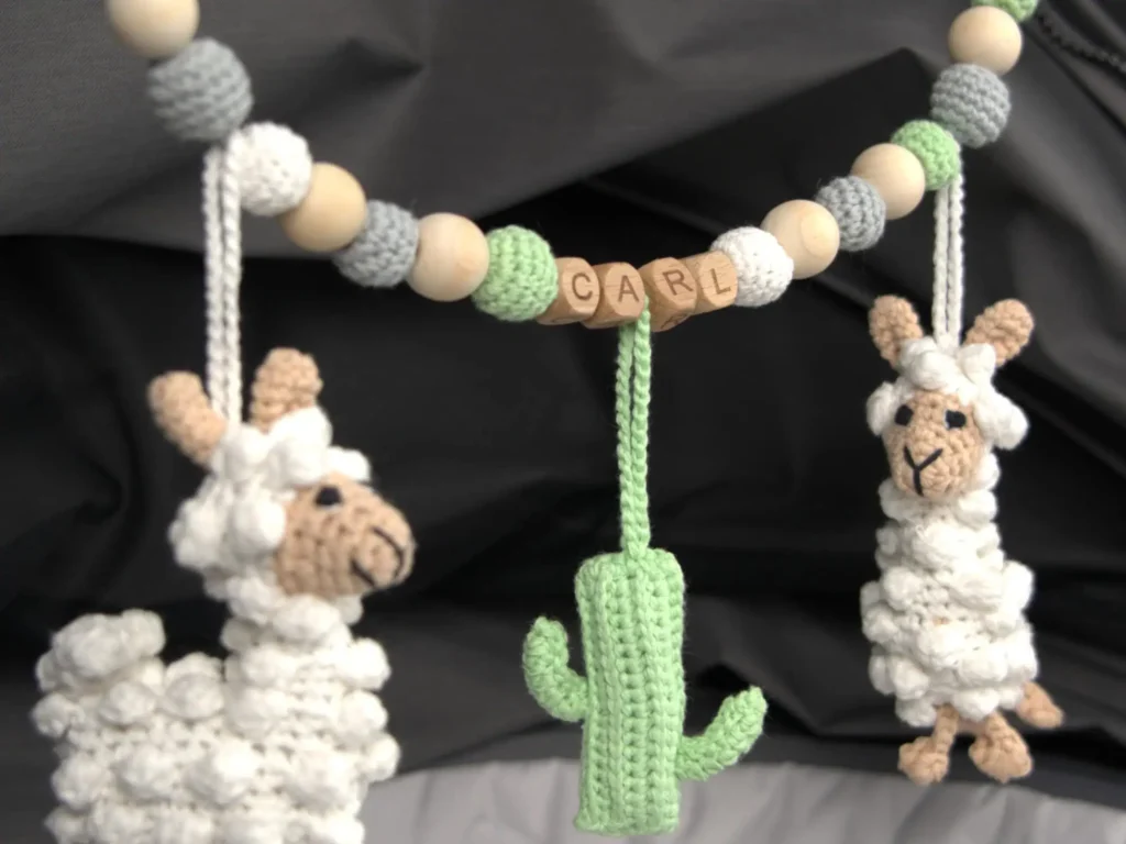 Personalisierte Kinderwagenkette im Kinderwagen mit Namen ‚Carl‘ und Lama-Motiv.
