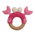 Crab PINCER rattle ring with crocheted yarn surface and untreated beechwood ring, back view isolated