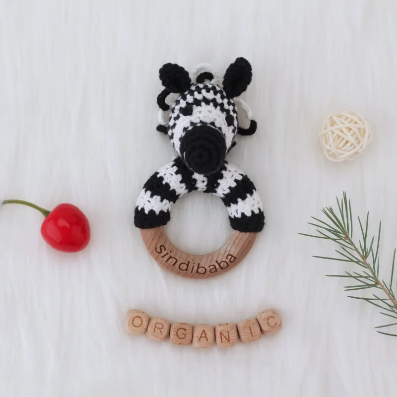 Rattle Ring Zebra STRIPEY – Decorative Lifestyle Scene Zebra STRIPEY rattle ring arranged on a decorative background with wooden and natural elements