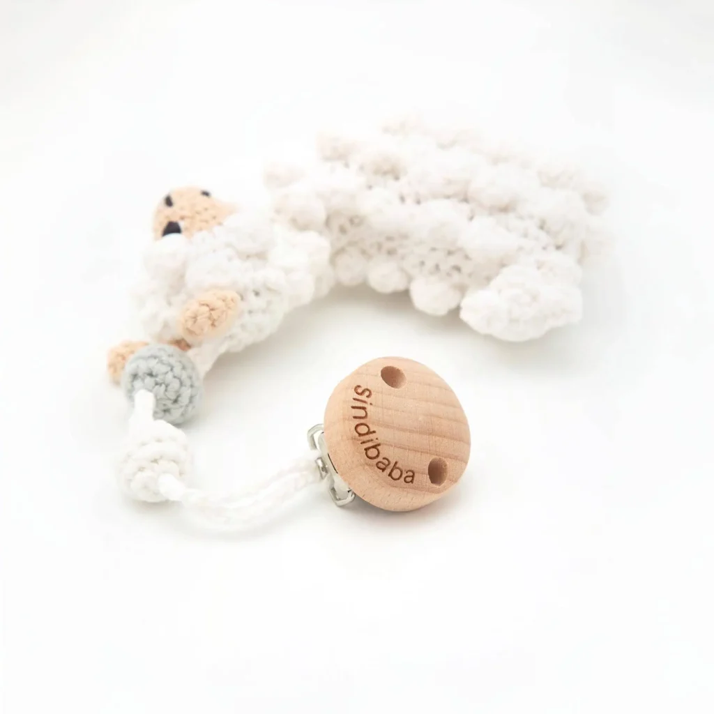 Stroller pendant llama, shot diagonally from above, focusing on the wooden clip with logo and the crocheted llama with textured surface