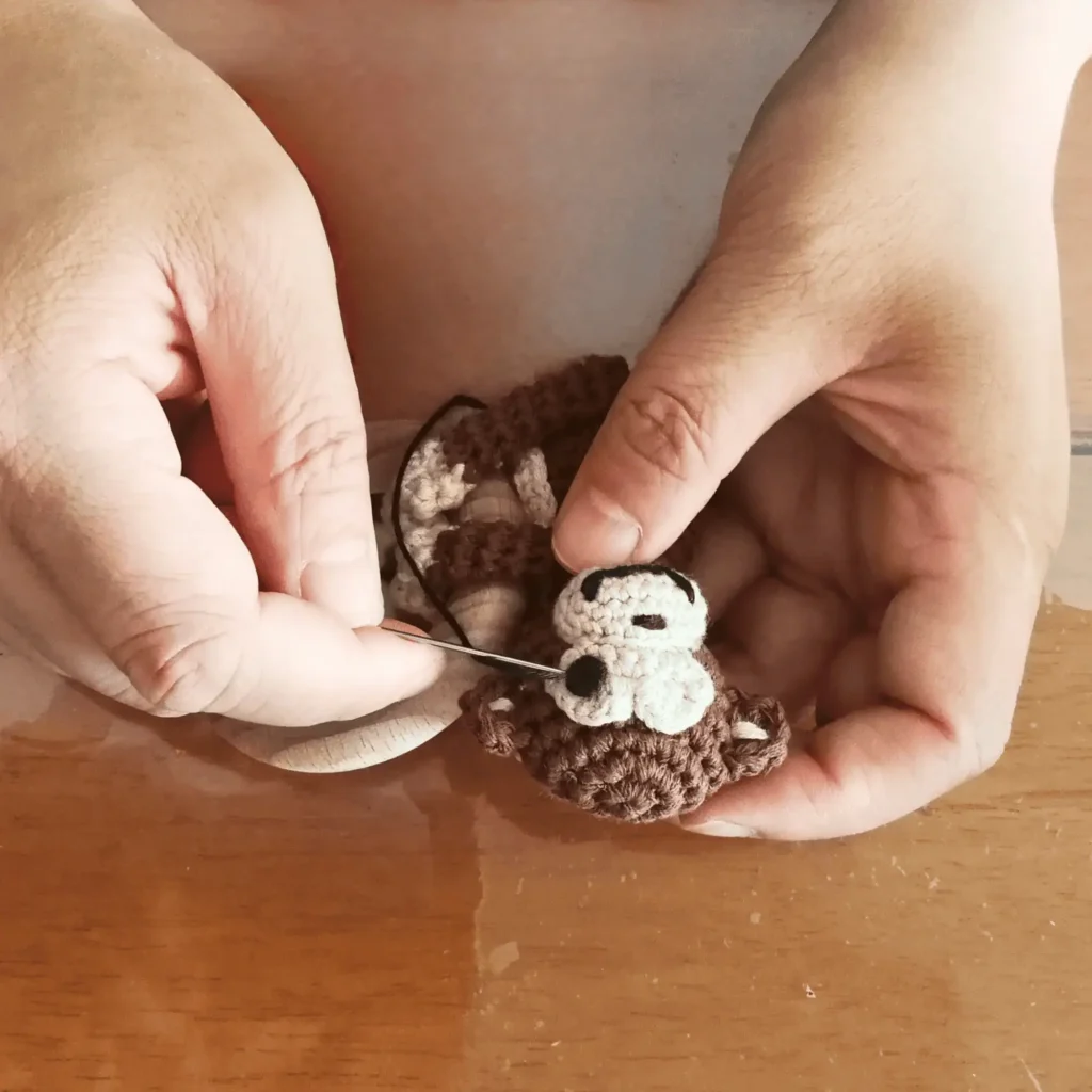 Eyes being embroidered by hand onto the hanging grasping toy Monkey CHARLIE, close-up of the craftsmanship.