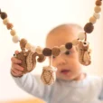 Baby greift von unten nach dem gehäkelten Eichhörnchen der Kinderwagenkette.
