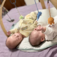 Gehäkelte Meerestier-Hängefiguren an einem Holz-Spielbogen über zwei Babys mit starker Unschärfe und Bokeh-Effekt.