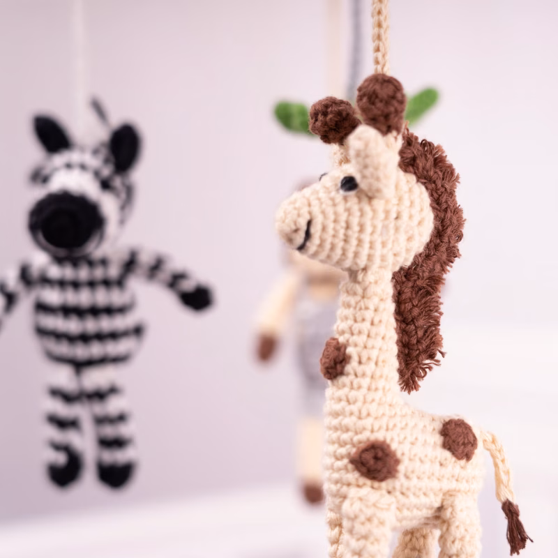 12540-baby-mobile-safari-2-closeup-zebra-giraffe Detailreiche Makroaufnahme der gehäkelten Giraffe und des Zebras im Vordergrund mit weichem Tiefenunschärfe-Hintergrund