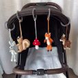 Praxisanwendung der fünf abnehmbaren gehäkelten Waldtier-Figuren, befestigt mit Ringen nebeneinander an einem Kinderwagen-Sonnenverdeck