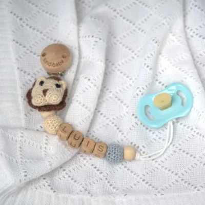 Personalized pacifier chain with lion motif and the name Luis (flatlay).