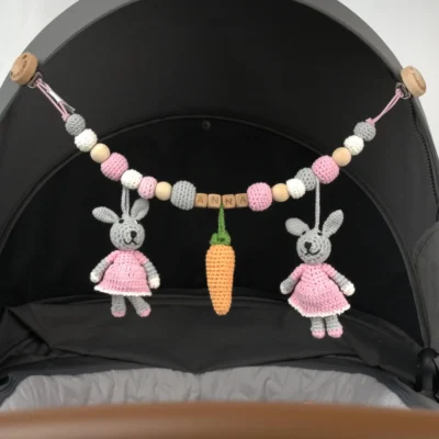 Personalized stroller chain with bunny motif and the name Anna attached to a stroller.