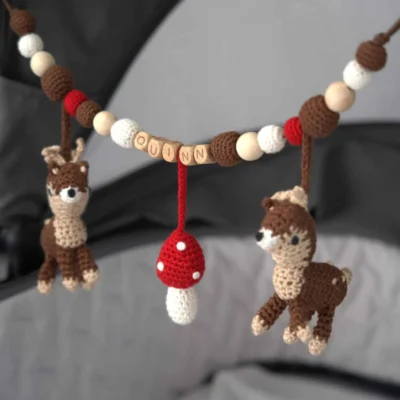 Personalized stroller chain with deer motif and the name Quinn attached to a stroller.