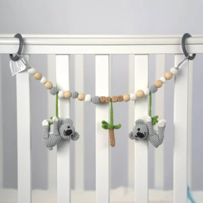 Personalized stroller chain with koala motif and the name Luis attached to a crib.