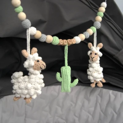 Personalisierte Kinderwagenkette mit Lama-Motiv und Namen Carl am Kinderwagen befestigt.