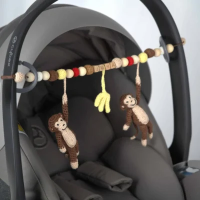 Personalized stroller chain with monkey motif and the name Juna attached to an infant carrier.
