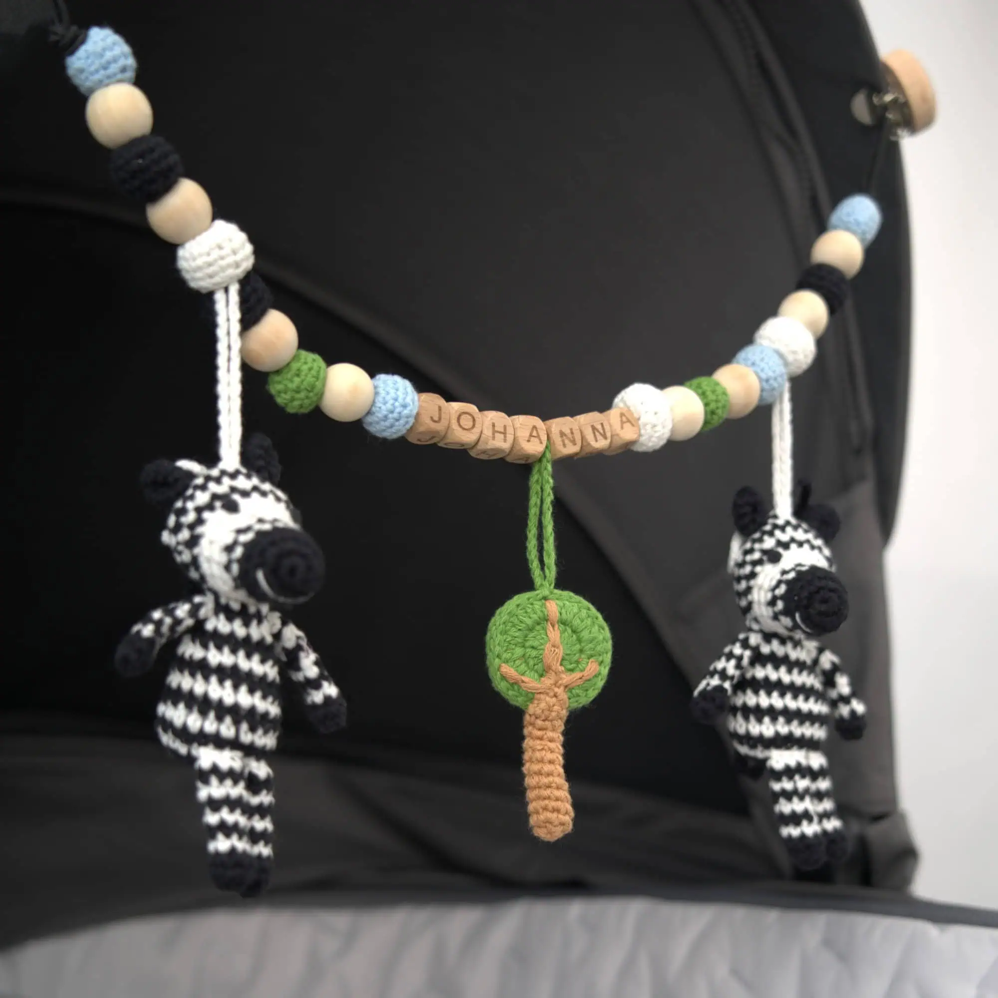 Personalisierte Kinderwagenkette mit Zebra-Motiv und Namen Johanna am Kinderwagen befestigt.