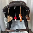 Praxisanwendung der fünf abnehmbaren gehäkelten Waldtier-Figuren, befestigt mit Ringen nebeneinander an einem Kinderwagen-Sonnenverdeck