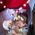 Dynamic lifestyle shot in a red and light blue stroller: The baby reaches for the chain, demonstrating the stretchiness of the elastic stroller chain.
